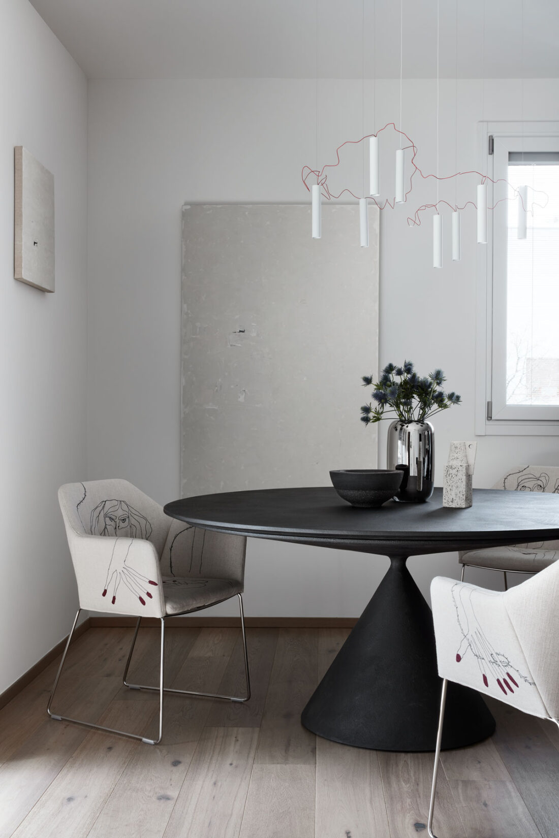 modern table with fabric chairs, artistic suspension lamp and two paintings